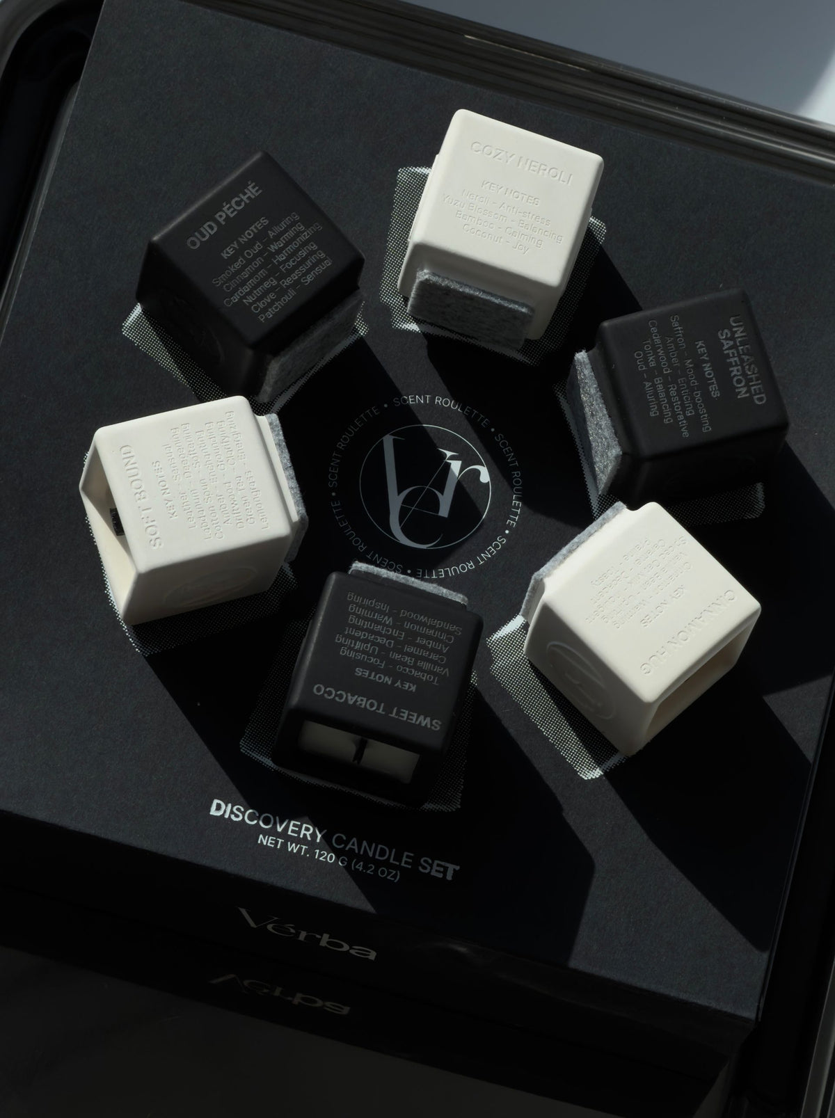 Six Vérba mini candles — Oud Péché, Cozy Neroli, Unleashed Saffron, Cinnamon Hug, Sweet Tobacco, Soft Bound — circled on the Discovery Set box