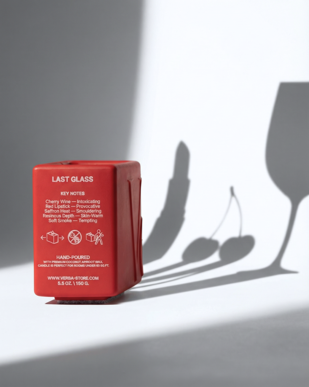 Red niche Verba candle with shadow of a wine glass and cherries on a gray background