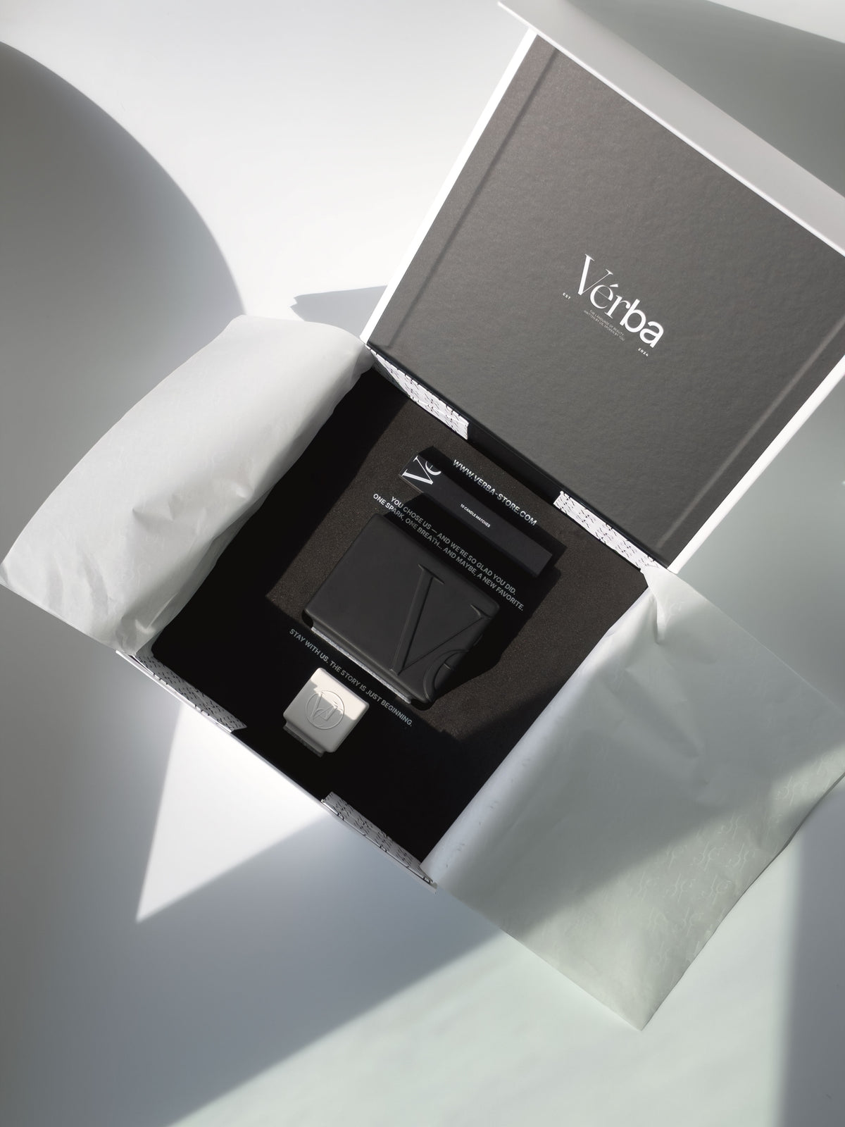 Verba black candle in an open gift box with black insert, wooden matches, a mini tester candle and white tissue paper