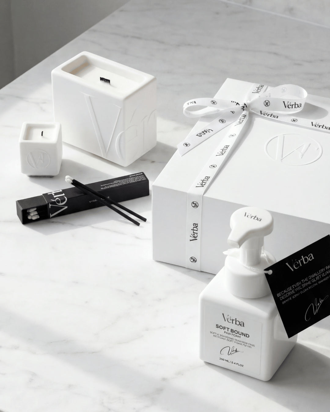 High end Vérba candle set on white marble — sculpted wooden wick candle, black matches and a white gift box with branded ribbon