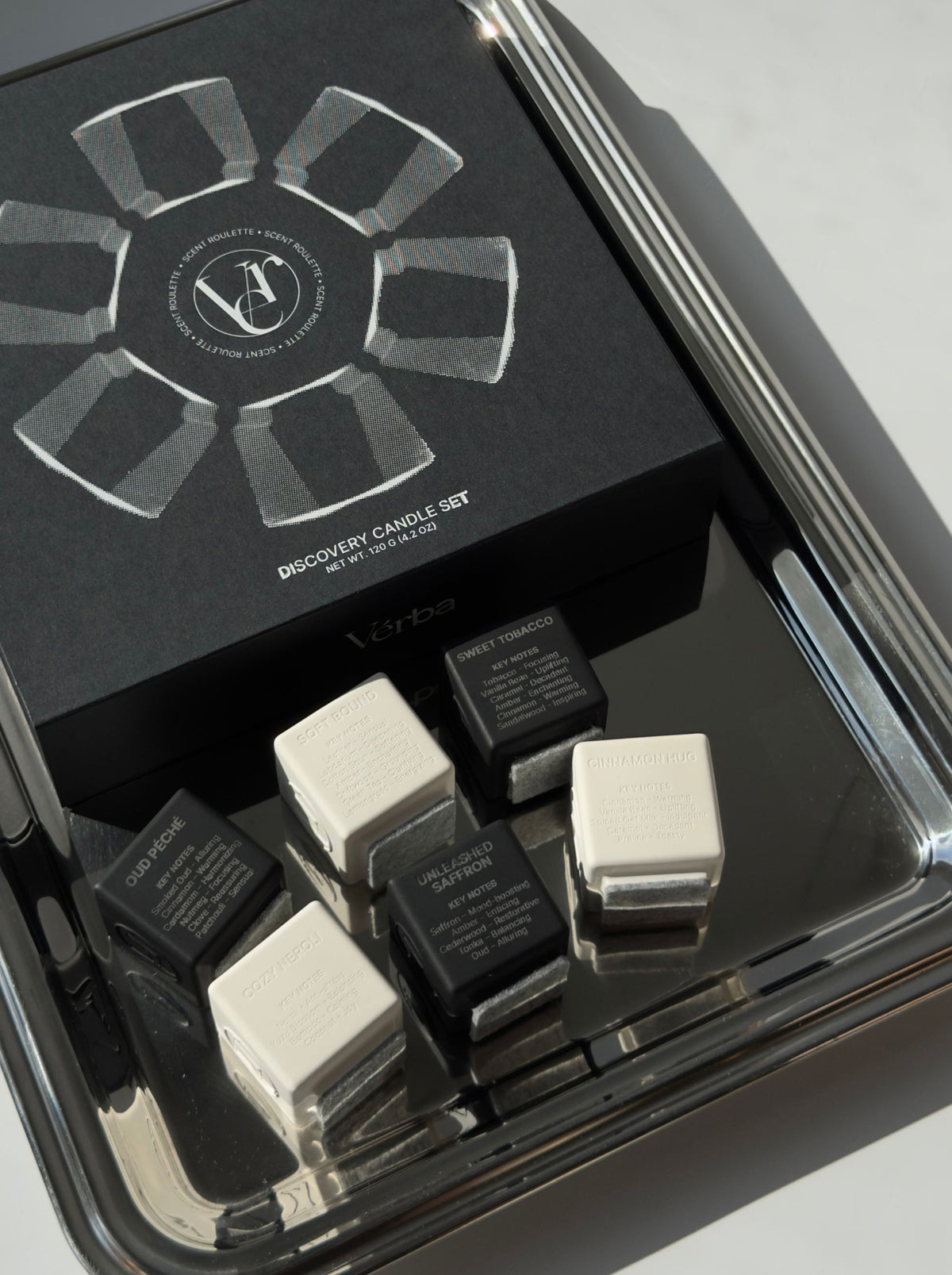 Verba Scent Roulette discovery candle set — black box on a chrome tray with six black and white mini candles in front
