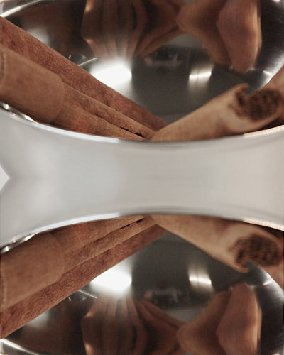 Stylish slow-motion video of cinnamon sticks and caramel swirling in a glass vessel, evoking the warm Cinnamon Hug candle fragrance.