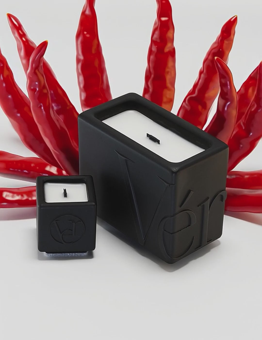 Black Verba candles surrounded by red chili peppers — Oud Péché fragrance video.