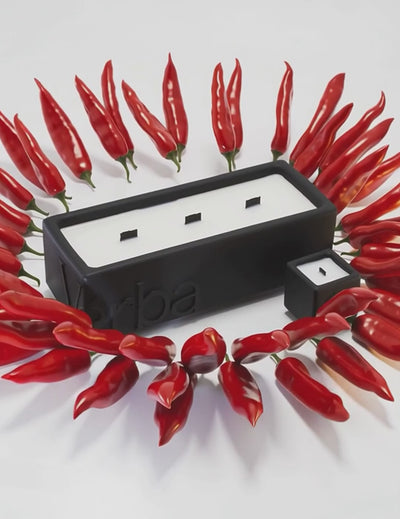 Large black Verba candle surrounded by red chili peppers — Oud Péché fragrance video.