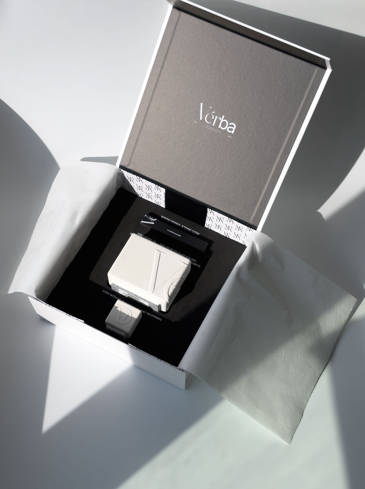 Verba white candle in an open gift box with black insert, wooden matches, a mini tester candle and white tissue paper